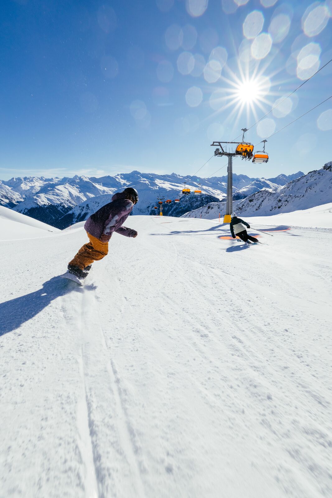 Border and skier going down the slopes in Davos Klosters ski area